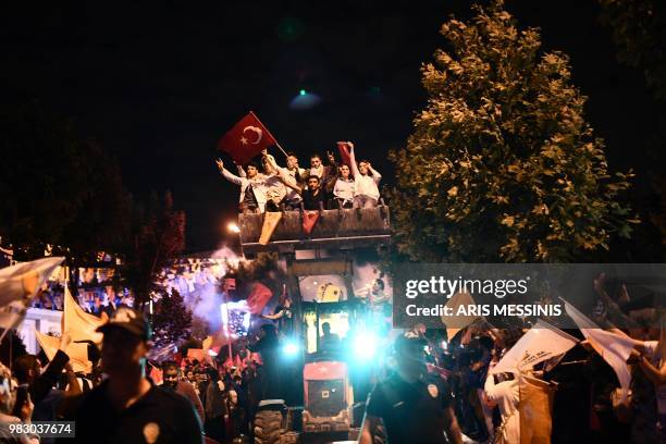 People react and wave Turkish flags outside the Justice and Development Party headquarters in Istanbul, on June 24 during the Turkish presidential...