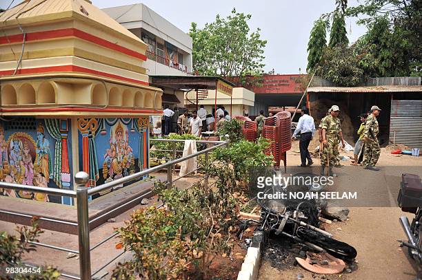 Indian police look at a burned motorcyle at the Hindu temple Shiv Mandir Goshala as communal violence continued in the Sha Ali Banda area of the old...