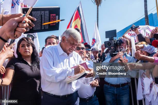 Andres Manuel Lopez Obrador, presidential candidate of the National Regeneration Movement Party , center left, autographs a book during the closing...