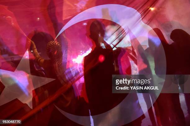 Silhouettes are seen through a Turkish flag as people react outside the Justice and Development Party headquarters in Istanbul, on June 24 during the...