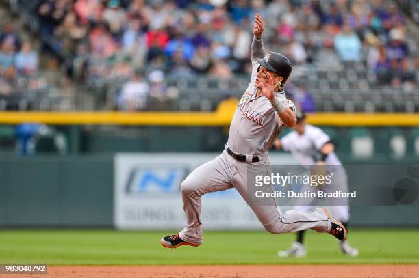 Derek Dietrich of the Miami Marlins jumps before sliding safely into third base after advancing from second base in the first inning of a game...
