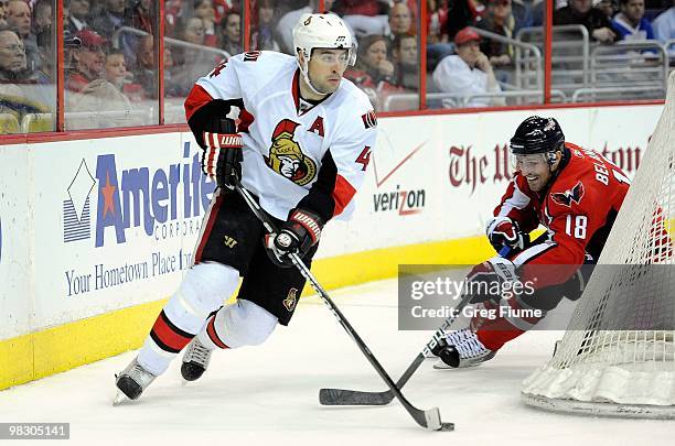 Chris Phillips of the Ottawa Senators handles the puck against Eric Belanger the Washington Capitals at the Verizon Center on March 30, 2010 in...