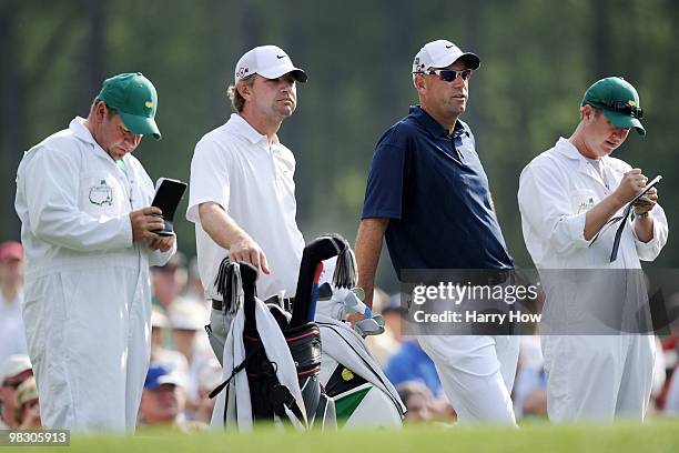 Lucas Glover and Stewart Cink look on alongside caddies during a practice round prior to the 2010 Masters Tournament at Augusta National Golf Club on...