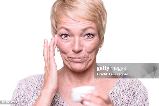 middle-aged woman applying anti-aging cream - anti aging imagens e fotografias de stock