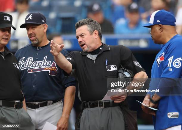 Home plate umpire Rob Drake goes over ground rules with bench coach Walt Weiss of the Atlanta Braves and bench coach DeMarlo Hale of the Toronto Blue...