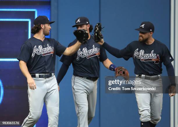 Charlie Culberson of the Atlanta Braves is congratulated by Ender Inciarte and Dansby Swanson after making a catch and crashing into the wall in the...