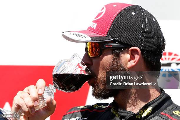 Martin Truex Jr., driver of the 5-hour ENERGY/Bass Pro Shops Toyota, celebrates in victory lane by drinking wine after winning the Monster Energy...