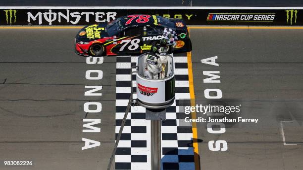 Martin Truex Jr., driver of the 5-hour ENERGY/Bass Pro Shops Toyota, crosses the finish line to win the Monster Energy NASCAR Cup Series Toyota/Save...