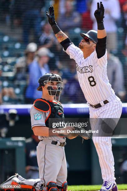 Gerardo Parra of the Colorado Rockies celebrates in front of J.T. Realmuto of the Miami Marlins after hitting a fourth inning solo homerun at Coors...