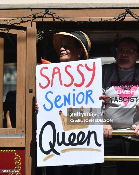 Man holds out a sign while rolling in a trolly car during the San Francisco gay pride parade in San Francisco, California on June 2018.