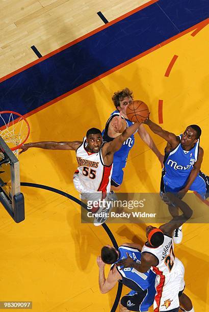 Reggie Williams of the Golden State Warriors goes up for a rebound against Rodrigue Beaubois and Dirk Nowitzki of the Dallas Mavericks during the...