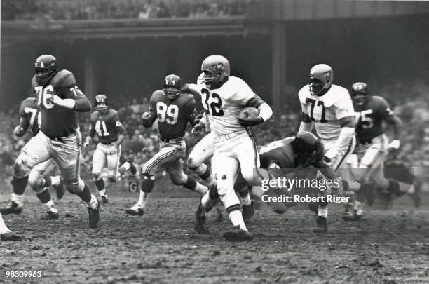 Jim Brown of the Cleveland Browns carries the ball as Willie Davis blocks and Rosie Grier and Cliff Livingston of the New York Giants pursue during a...