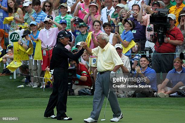 Gary Player of South Africa congratulates Arnold Palmer for sinking his putt during the Par 3 Contest prior to the 2010 Masters Tournament at Augusta...