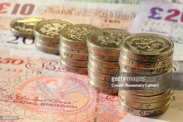 stacks of one pound coins on pound notes. - haslemere stock-fotos und bilder