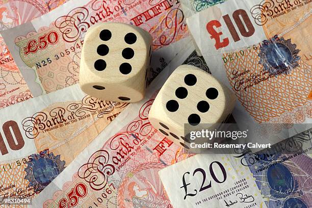 two dice, two sixes, background of pound notes. - haslemere stock-fotos und bilder