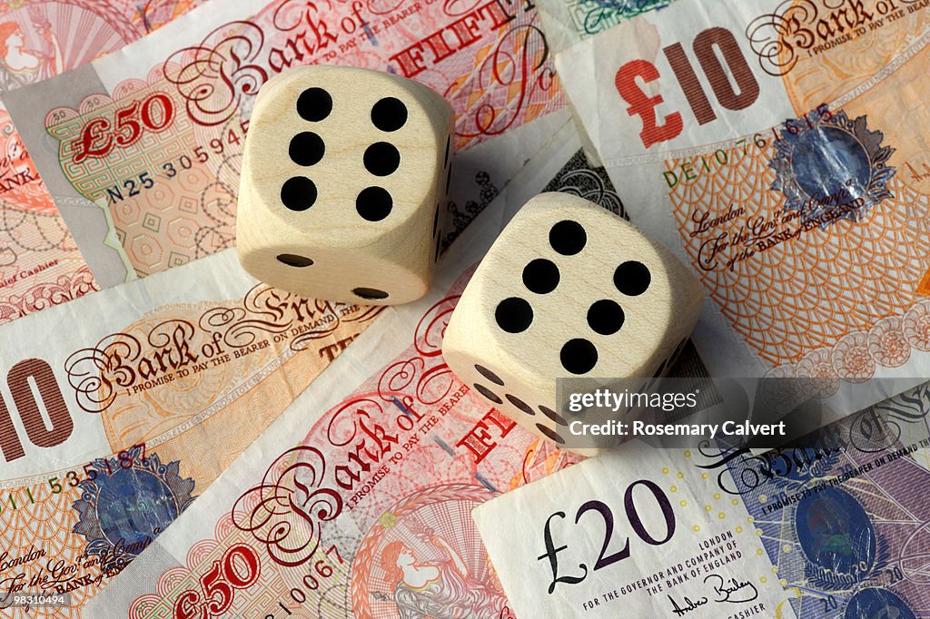 Two dice, two sixes, background of pound notes.