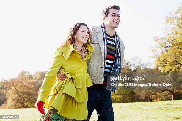 couple hugging and walking in sunny field - robert a daly bildbanksfoton och bilder