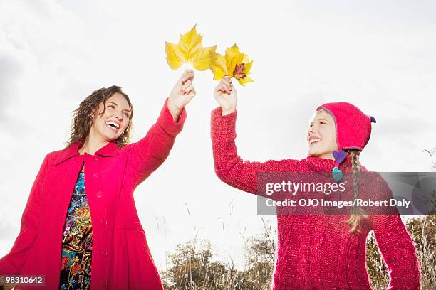 mother and daughter holding autumn leaves - robert a daly bildbanksfoton och bilder