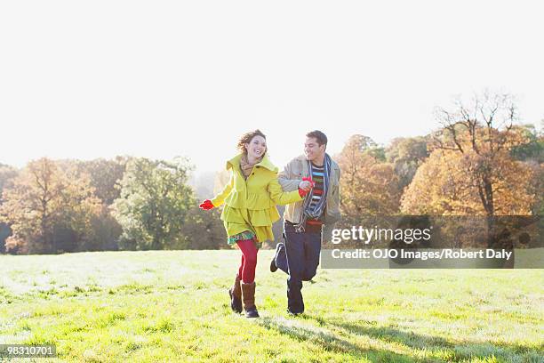 couple holding hands and running in sunny field - robert a daly bildbanksfoton och bilder