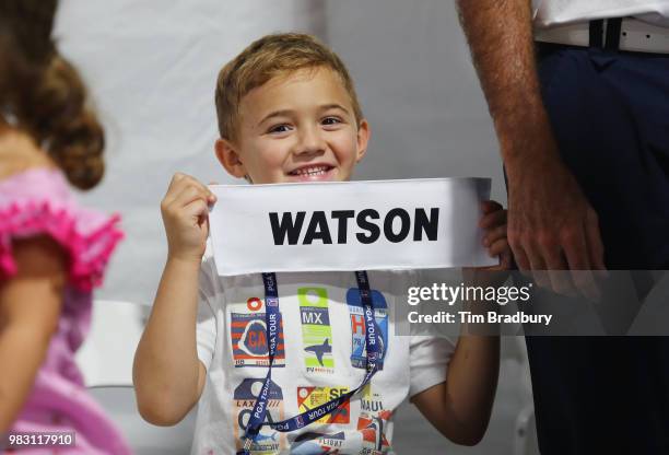 Caleb Watson, son of Bubba Watson of the United States, holds his father's nameplate after the final round of the Travelers Championship at TPC River...