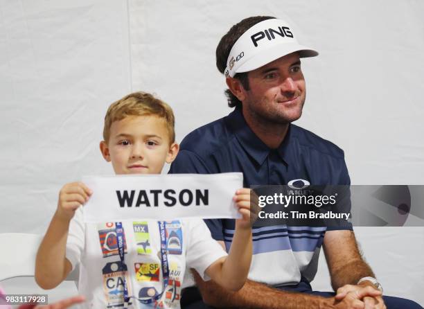 Caleb Watson, son of Bubba Watson of the United States, holds his father's nameplate after the final round of the Travelers Championship at TPC River...