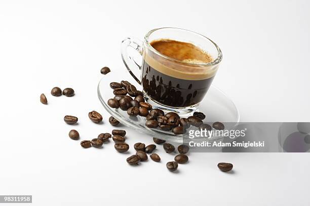 cup of espresso shot with crema and some coffee beans - color crema stockfoto's en -beelden