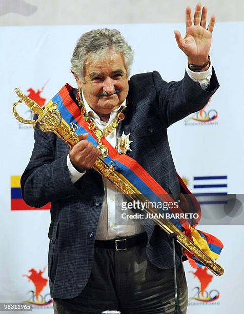 Uruguayan president Jose Mujica waves after receiving a replica of Simon Bolivar's sword and the Simon Bolivar decoration from his Venezuelan...