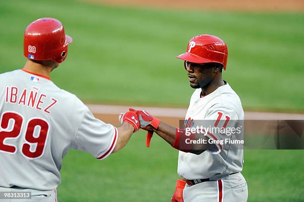 Jimmy Rollins of the Philadelphia Phillies is congratulated by teammate Raul Ibanez after scoring against the Washington Nationals at Nationals Park...