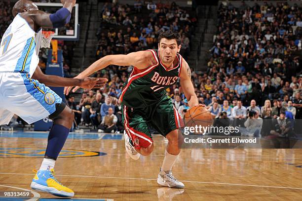 Carlos Delfino of the Milwaukee Bucks drives to the basket against Johan Petro of the Denver Nuggets during the game at Pepsi Center on March 20,...