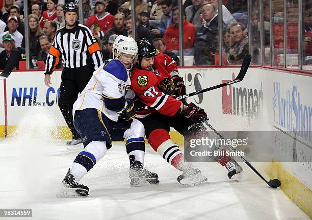 Adam Burish of the Chicago Blackhawks controls the puck defended by Paul Kariya of the St. Louis Blues on April 07, 2010 at the United Center in...