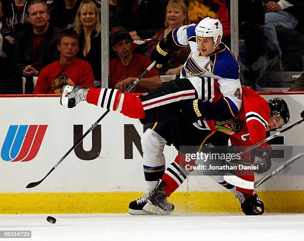 Jonathan Toews of the Chicago Blackhawks is dumped by Eric Brewer of the St. Louis Blues as they battle for the puck at the United Center on April 7,...