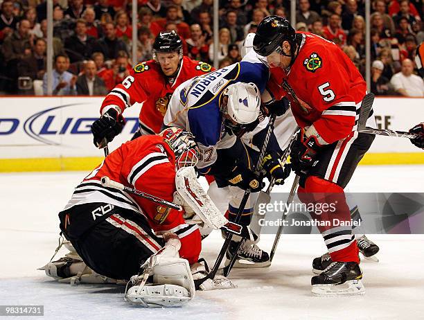 David Perron of the St. Louis Blues tries to dig out the puck from underneath Antti Niemi of the Chicago Blackhawks as Brent Sopel assists at the...