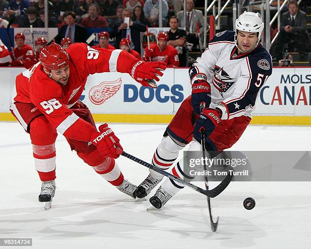 Fedor Tyutin of the Columbus Blue Jackets tries to keep control of the puck away from Tomas Holmstrom of the Detroit Red Wings during an NHL game at...