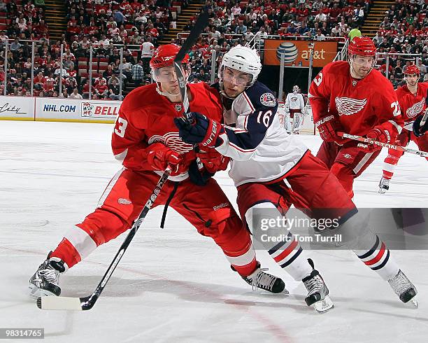 Derick Brassard of the Columbus Blue Jackets and Darren Helm of the Detroit Red Wings get tied up during an NHL game at Joe Louis Arena on April 7,...