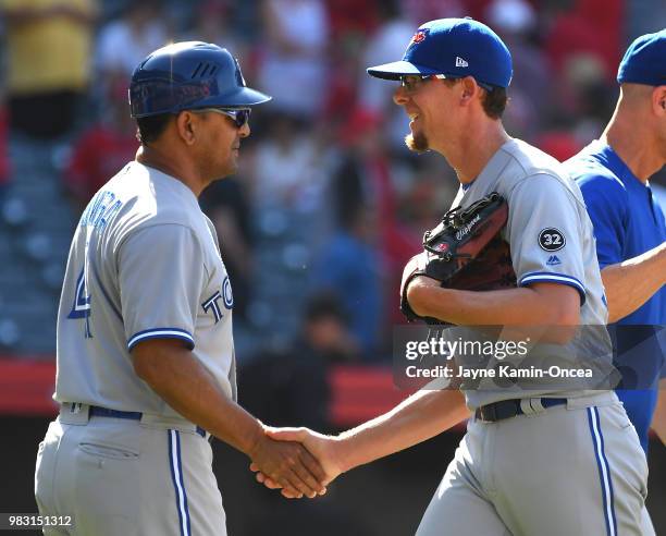 Tyler Clippard shakes hands with third base coach Luis Rivera of the Toronto Blue Jays after earning a save in the tenth inning of the game against...