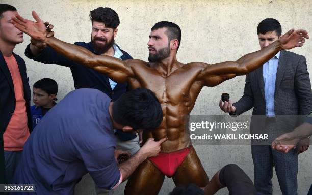 This photo taken on April 18, 2018 shows Afghan bodybuilder Hares Mohammadi being covered in fake tan during a bodybuilding and fitness contest in...