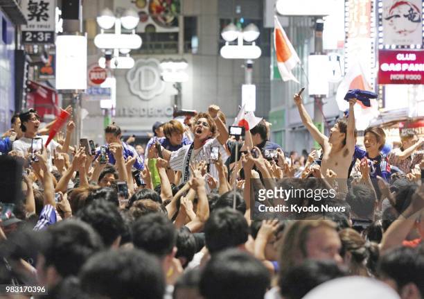 Football fans celebrate Japan's 2-2 draw with Senegal in World Cup Group H, taking to the streets in Tokyo's Shibuya entertainment district in the...