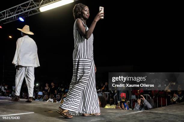 Designer Adama Paris takes pictures with her phone after her show during last day of the Dakar Fashion Week at the working class suburb of Keur...