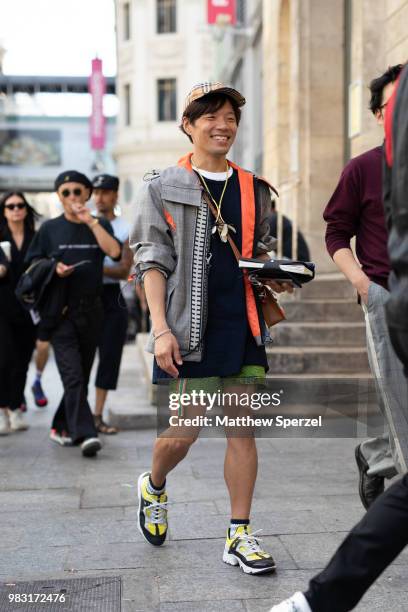 Is seen on the street during Paris Men's Fashion Week S/S 2019 wearing grey/orange coat with green shorts on June 24, 2018 in Paris, France.