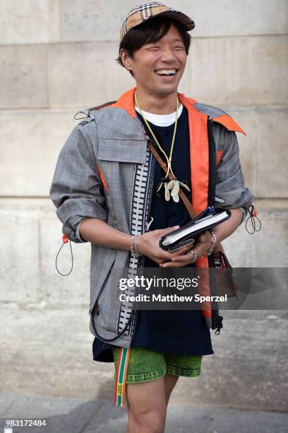 Is seen on the street during Paris Men's Fashion Week S/S 2019 wearing grey/orange coat with green shorts on June 24, 2018 in Paris, France.