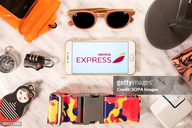 In this photo illustration, the Spanish low-cost airline owned by Iberia, Iberia Express, logo is displayed on a smartphone screen next to different...
