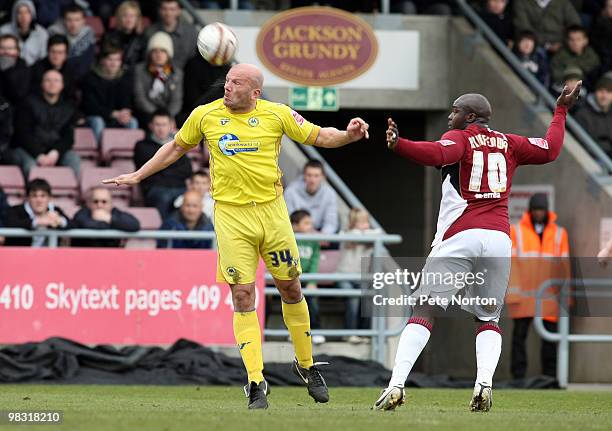 Guy Branston of Torquay United heads the ball away from Adebayo Akinfenwa of Northampton Town during the Coca Cola League Two Match between...