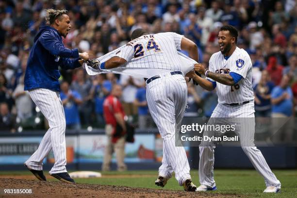 Orlando Arcia and Domingo Santana of the Milwaukee Brewers attempt to take the jersey off of Jesus Aguilar after Aguilar hit a walk-off home run to...