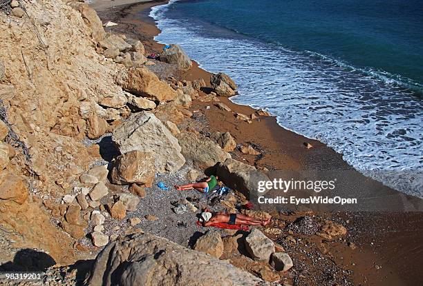 Tourists taking a sunbath at Akra beach with Kap Furni near Monolithos on July 16, 2009 in Rhodes, Greece. Rhodes is the largest of the Greek...