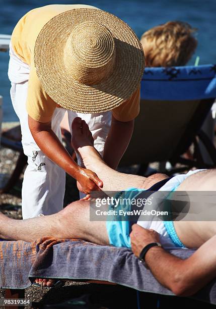 Woman offers massage for tourists on Rhodes city beach on July 16, 2009 in Rhodes, Greece. Rhodes is the largest of the Greek Dodecanes Islands.