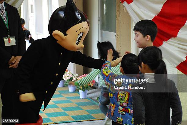 In this handout image provided by the Board of Education, Shinjuku City, Japanese famous cartoon character Tetsuwan Atom or Astro Boy pats a child's...