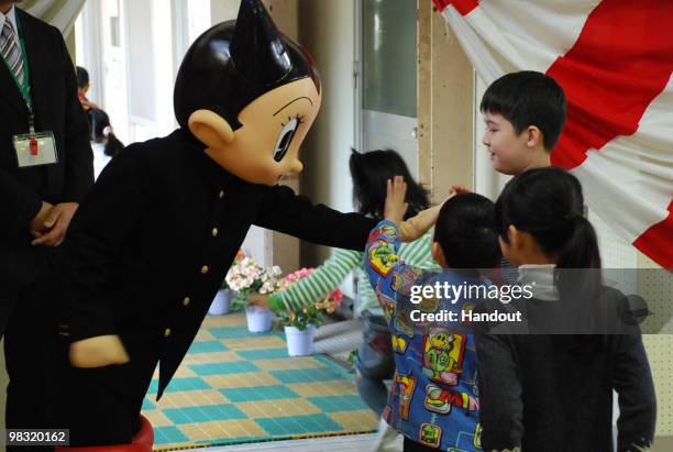 In this handout image provided by the Shinjuku City Board of Education, Japanese famous cartoon character Tetsuwan Atom or Astro Boy pats a child's...