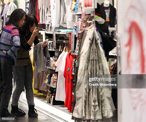 Customer looks at clothing with a salesclerk at Fast Retailing Co.'s Uniqlo store in the Ginza district of Tokyo, Japan, on Thursday, April 8, 2010....