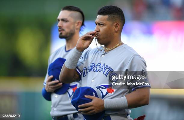 Randal Grichuk stands next to Yangervis Solarte of the Toronto Blue Jays as he kisses the crucifix around his neck before playing the Los Angeles...