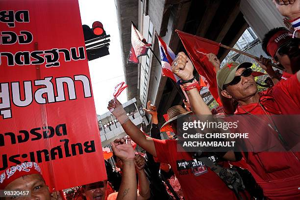 Anti-government protesters wave national flags and clappers as they celebrate after riot police retreated during a rally in central Bangkok on April...